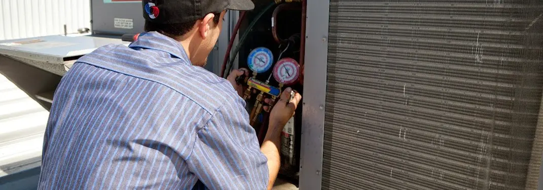 HVAC technician servicing a condenser unit in Sterling
