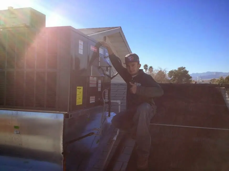HVAC technician performing AC Tune-Up on a rooftop unit in Sterling